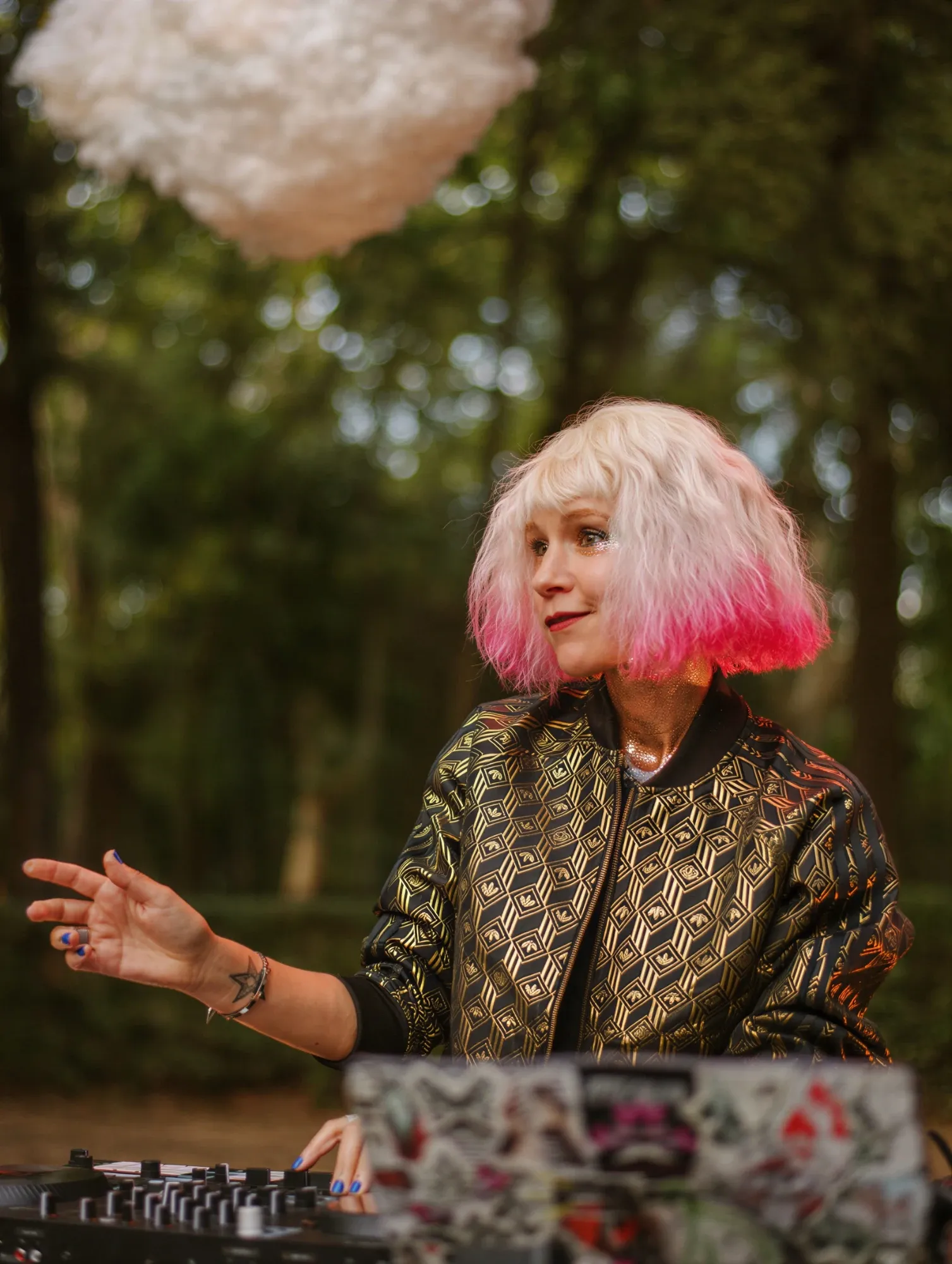 Emeraldia at the decks outdoors, blonde hair with pink tips, golden jacket, under a hanging cloud