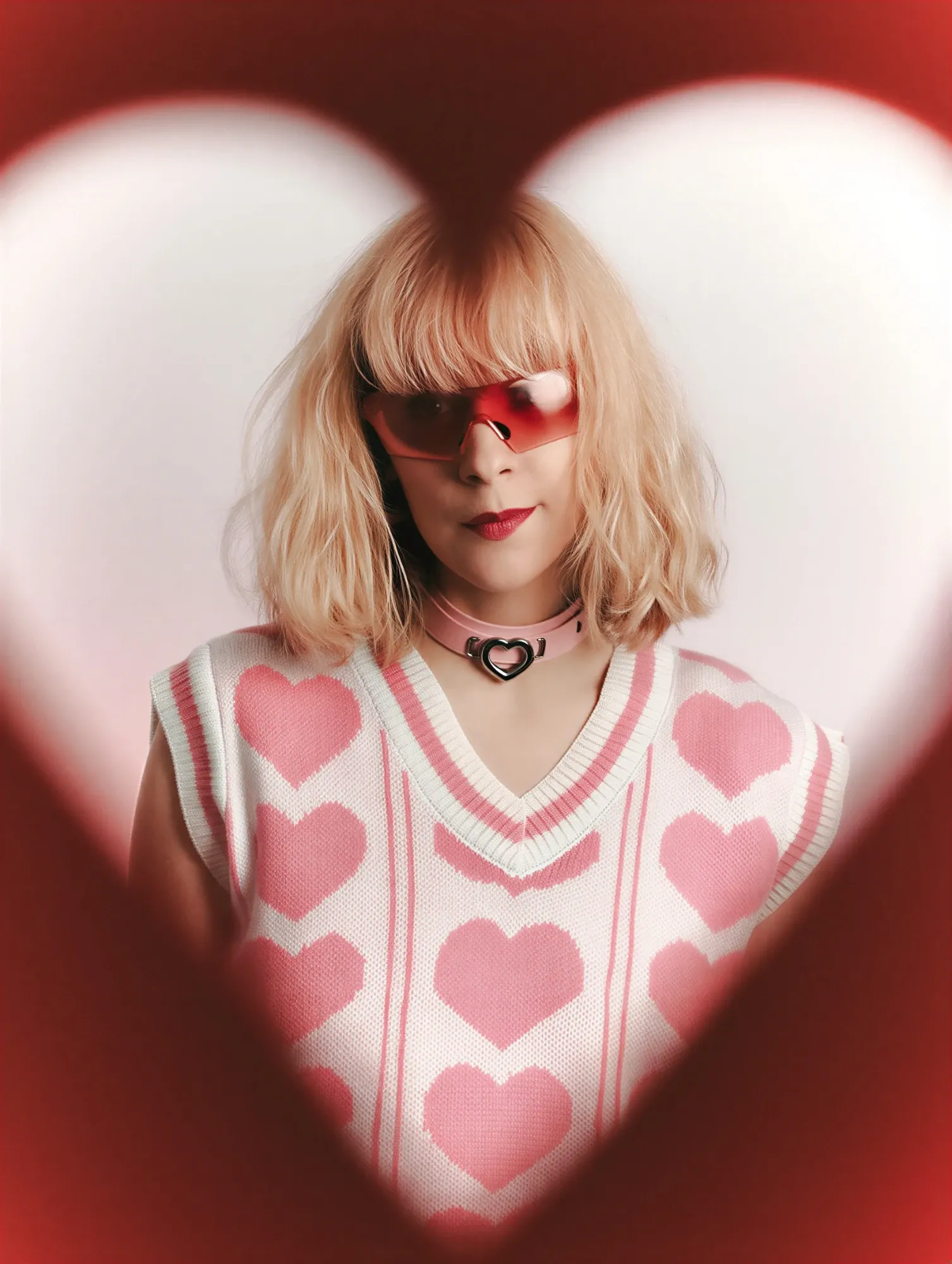 Emeraldia in a heart-shaped frame, red glasses, sleeveless jumper with a heart pattern