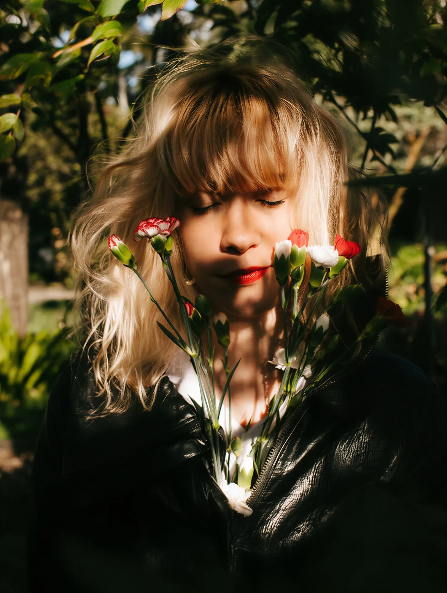 Emeraldia with eyes closed, a bouquet of red and white carnations, under the leaves